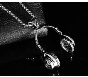 Macro detail of music headphone pendant on box chain over black textured leather