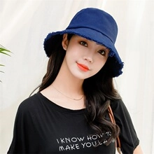 Detailed close-up of dark blue denim bucket hat with distressed frayed edge design