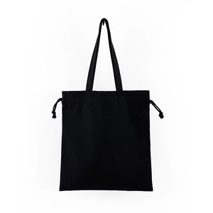 Detailed view of the dual carrying straps and drawstring closure on black canvas tote bag
