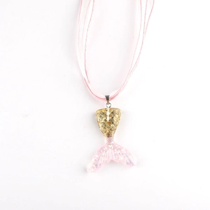 Detail of mermaid tail pendant with golden scales and pink glitter on a ribbon necklace