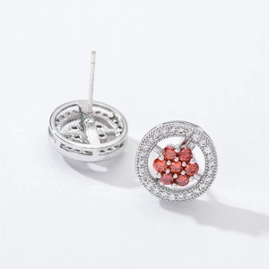 Macro view of floral silver earrings with red zircon center and halo crystal stones