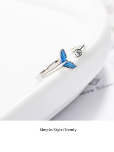Close-up of silver fishtail ring with blue enamel and crystal on a white plate