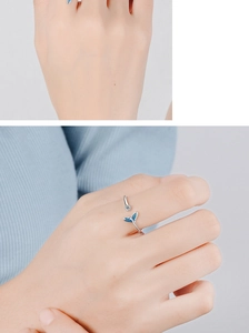 Detail of silver fishtail ring with blue inlay and small diamond on woman's finger
