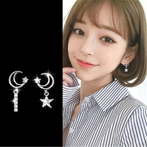 Detailed view of asymmetric silver moon and star earrings with sparkling rhinestones