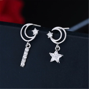 Macro shot of asymmetrical silver moon and star earrings with sparkling cubic zirconia