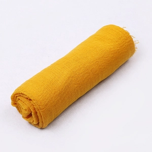 Macro detail of yellow crinkle cotton linen scarf roll with soft fringed edge textures