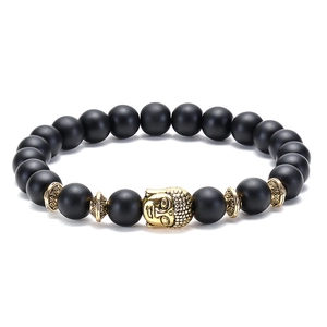 Detailed view of matte black 8mm beads and golden Buddha head on an elastic bracelet