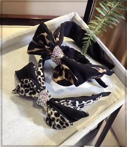 Detail of leopard print bow headbands with rhinestones on a grey display tray