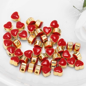 Polished gold-framed red heart beads for DIY bracelet jewelry making in ceramic tray