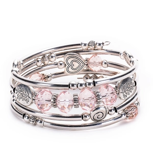 Detail of pink crystal wrap bracelet featuring silver metal heart and tree of life charms