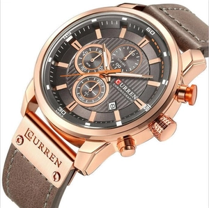 Close-up of CURREN men's rose gold chronograph watch with brown leather strap and grey dial