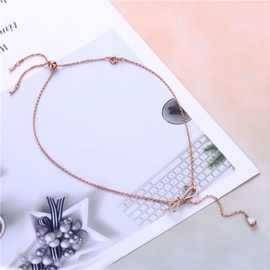 Detail of rose gold bow necklace with teardrop charm and crystals on a white magazine
