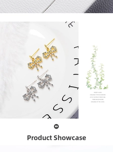 Detailed close-up of gold and silver bow stud earrings with rectangular zircon stones
