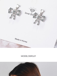 Detail of silver bow earrings with zircon stones including a model wearing display