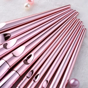 Detail of pink metal makeup brush set arranged on white faux fur with pearls