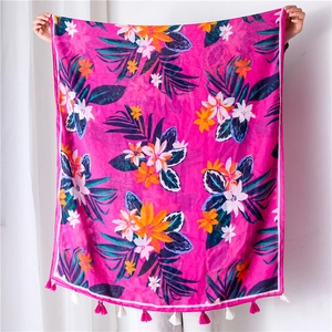 Detail of tropical plant print and pink tassels on vibrant rose red cotton linen scarf