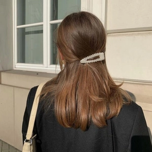 Detail of white pearl hair clip with rectangular hollow design worn by a model