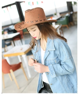 Detailed view of a brown suede cowboy hat featuring black cross-stitch edges and a chin cord