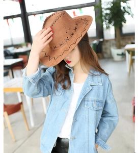 Detail of a brown cowboy hat with cross stitching and a classic blue denim jacket