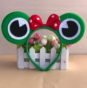 Detail of plush frog headband with large eyes and polka dot bow for costume parties