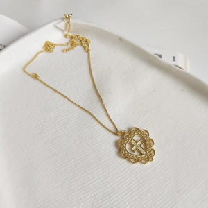 Detail of gold cross pendant inside a hollow heart frame on a white ceramic plate