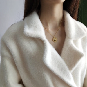 Detailed close-up of a golden heart necklace with a cross charm on a female model