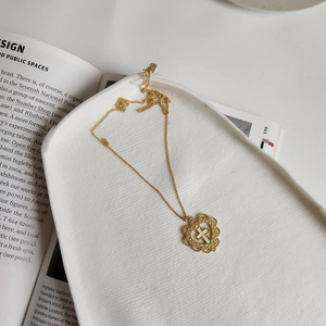 Macro detail of a gold plated 925 silver heart necklace with cross on white ceramic tray