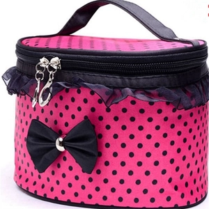 Pink polka dot makeup bag with black lace trim and bow on a white background