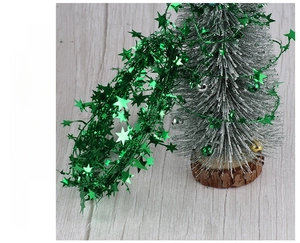 Close-up of green star tinsel garland and a miniature flocked silver Christmas tree