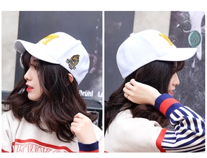 Detail of yellow M embroidery and tiger patch on white cotton baseball cap for women