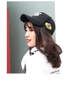 Detail of black baseball cap featuring golden B letter embroidery and side bee patch decor