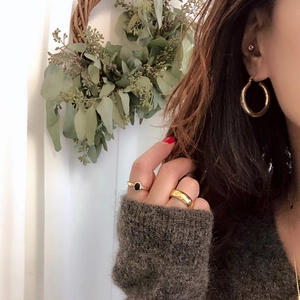 Close-up of elegant gold hoop earrings and rings worn with a cozy knit sweater