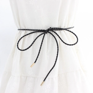 Minimalist black braided waist belt with gold metal tips styled on a floral dress