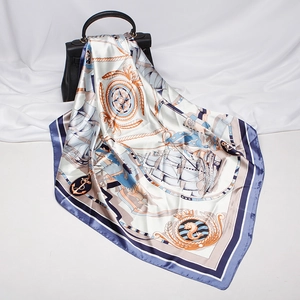 Detail of nautical print silk scarf with anchors and sailboats on a black leather handbag