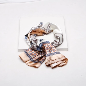 Artistic detail of premium silk-feel scarf with elegant chain and geometric prints