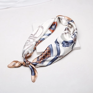 Detailed close-up of a knotted silk scarf featuring blue and orange equestrian patterns