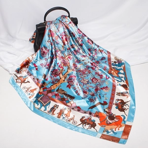 Detail of blue silk-like square scarf with intricate floral and animal prints on a handbag