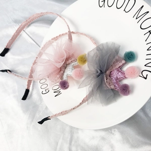 Detail of pink and grey sequin crown headbands with colorful pom-poms on a ceramic plate