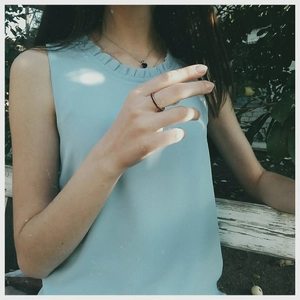 Detail of silver heart pendant necklace and stone ring on model wearing light blue top