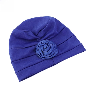 Vue détaillée d'un turban bleu marine avec une grande rose en tissu et des plis texturés