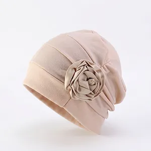 Détail du turban beige montrant la texture et la grande fleur en tissu 3D