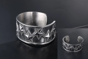 Detailed close-up of a silver punk star pattern on a wide titanium steel cuff bracelet
