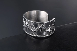 Detail of silver pentagram embossed steel cuff bracelet with beaded edges on leather