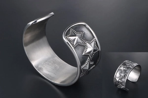 Detail of vintage punk stainless steel cuff bracelet with embossed stars and textured edges