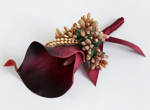 Close-up of burgundy Calla Lily boutonniere with golden berries and rhinestone ribbon decor
