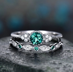 Macro view of emerald green zircon ring set on dark stone with bokeh background
