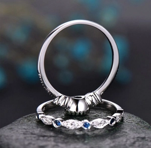 Macro shot of silver crown ring set with blue and white marquise stones on stone