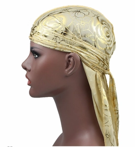 Detail of golden rose print silky durag with wide straps and metallic satin finish
