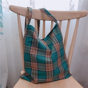 Détail du grand espace intérieur du sac cabas à carreaux vert sur une chaise en bois