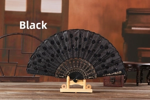 Detail of a black lace folding fan with sequins and intricate hollowed-out patterns on ribs
